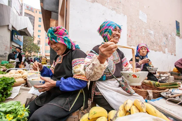 Um grupo de mulheres chinesas seniores vendedor comer macarrão durante vende frutas frescas e vegetais . — Fotografia de Stock