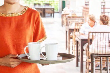 Kadın garson elinde bir tepsi kahve tutuyor..