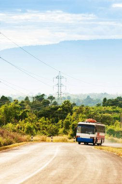 Bolaven Platosu 'nun dağ yolundan Laos ve Vietnam sınırına doğru giden yerel bir otobüs. Arka planda akşam karanlığında resimli bir dağ..