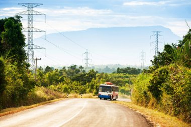 Bolaven Platosu 'nun dağ yolundan Laos ve Vietnam sınırına doğru giden yerel bir otobüs. Arka planda akşam karanlığında resimli bir dağ..