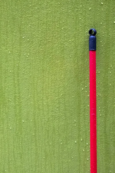 Κόκκινη Σφουγγαρίστρα Ακουμπισμένη Στον Βρεγμένο Πράσινο Τοίχο Στη Βροχή — Φωτογραφία Αρχείου