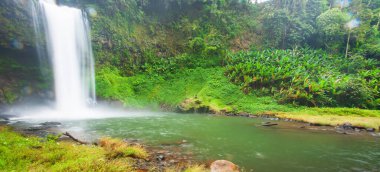 Yağmurlu bir sabahta taze tropik şelale, tatlı su sıçrıyor ve vadideki havaya üflüyor. Bolaven Platosu, Pakse, Laos. Uzun pozlama.