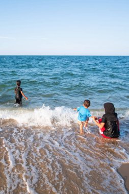 Mutlu Müslüman aile, güneşli bir yaz günü okyanus sörfünde oynuyor. Narathiwat, Güney Tayland 'da resim mavisi deniz..