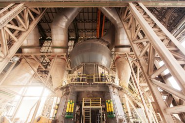 İki erkek mühendis koruyucu ekipman giyip bir fabrikada büyük makineleri tamir ediyor..