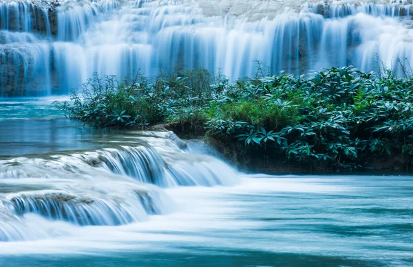Relaxing by a tropical waterfall in the morning, gently freshwater flowing on limestone layers. Long exposure.