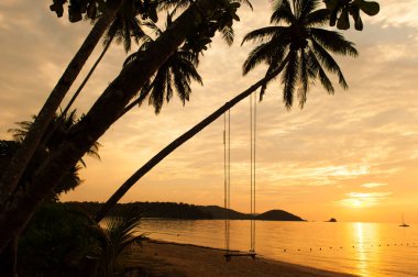 Yazın alacakaranlıkta sakin bir tropikal adanın manzarası, hindistan cevizi palmiye ağaçlarının silueti ve dramatik günbatımı gökyüzüne karşı sallanma. Koh Mak Adası, Tayland.