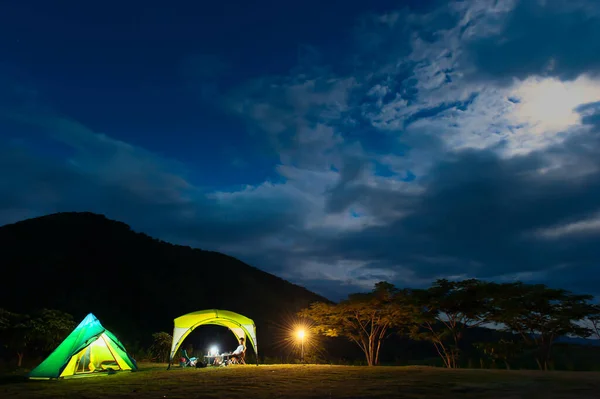 Landscape of illuminated camp tents under the moonrise, camping on a hill under the moonbeam. Soft focus.