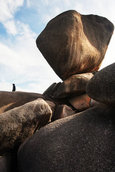 An unidentified female tourist stands on the precipice on summer morning, magical large rock on the precipice. Similan Islands, travel destinations in South Thailand.