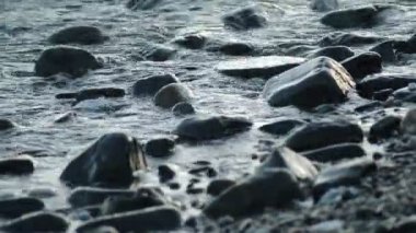 Taş ve çakıl taşları son ışığı, dalgalar deniz tarafından gün banyo