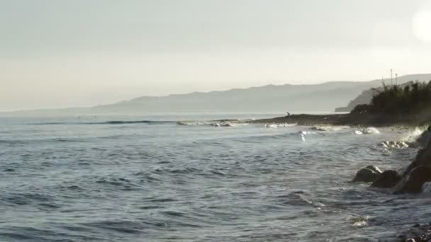 海浪打破岩石和穆斯林人祈祷古兰经在日落 — 图库视频影像