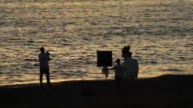 Fotoğrafçı sahil üzerinde yeni evli çift ile fotoğrafları günbatımında yapma