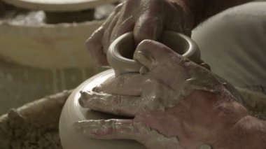 Potter ustası yeni bir vazonun boynunu ve ağzını çamur ya da kille kaplıyor.