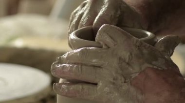 Potter ustası torna tezgahında yeni bir vazonun ağzını ve boynunu şekillendiriyor.