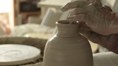 Potter, yeni bir vazonun ağzını ve boynunu çamurda şekillendiriyor.