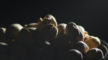 Siyah arka planda kıvrılan fıstıklar samimi bir ışık.