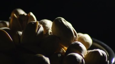 Fıstıklar, kurutulmuş meyveler, siyah arka planda dönmeler.