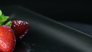 Siyah arka planda dönen doğal çilekler.