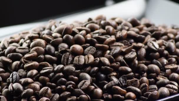 Kávová zrna kroužící na černém podnosu