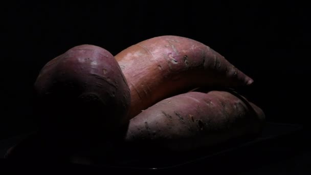 黒の背景に生のサツマイモのギザギザ イポモアバタータ — ストック動画
