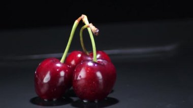 Siyah arka planda dönen üç kiraz