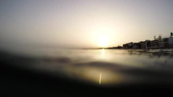 波がゆっくりと夕日のビーチに浮かぶ 一人称視点 — ストック動画