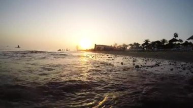 Akdeniz dalgaları gün batımında sahile ulaşır.