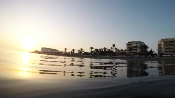海滩波涛汹涌 海岸线上的建筑物日落时分 — 图库视频影像