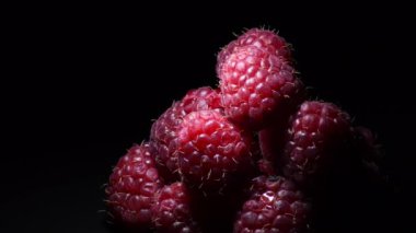 Siyah arka planda dönen kırmızı ahududular ve samimi ışık