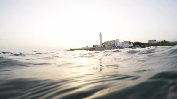 Leuchtturm Vom Meer Zwischen Wellen Bei Sonnenuntergang — Stockvideo