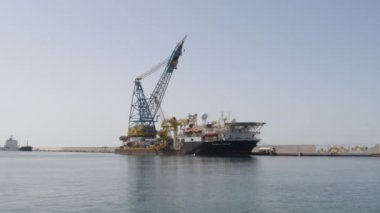 Büyük ticaret gemisi güneşli bir günde büyük bir vinçle limana demir attı.