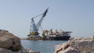 Büyük bir ticaret gemisi büyük bir vinçle limana demirlemiş.