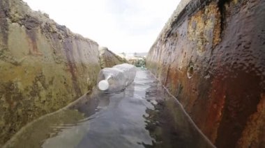 Limandaki bir su kanalında plastik şişe ve çöp.