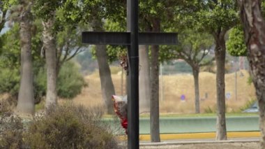 Çiçeklerle siyah demir haç. Arabalarla dolu bir yol.