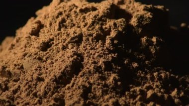 Siyah arka planda dönen toz tarçın, yiyecek baharatı
