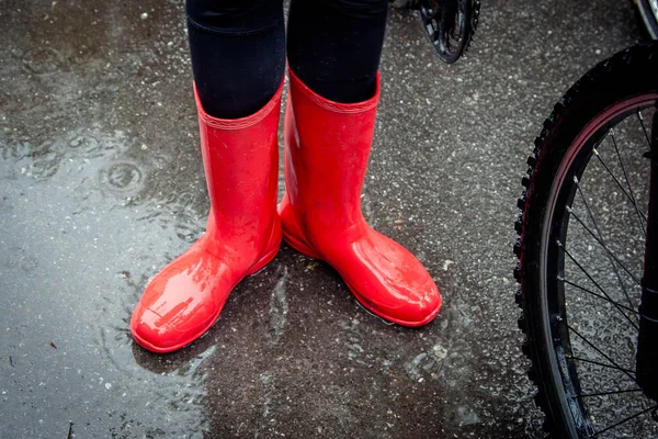 Feeling protected in her boots. Close-up of woman in red rubber boots  on the puddle