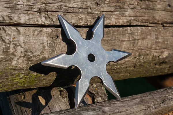 Shuriken (throwing star), traditional japanese ninja cold weapon stuck in wooden background