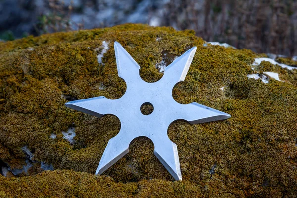 Shuriken (throwing star), traditional japanese ninja cold weapon stuck in wooden background