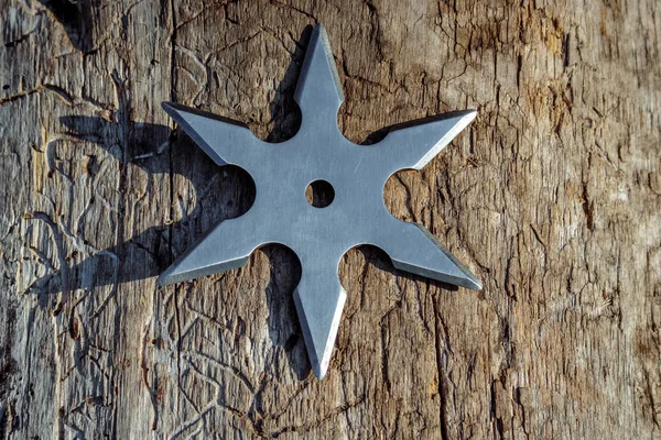 Shuriken (throwing star), traditional japanese ninja cold weapon stuck in wooden background