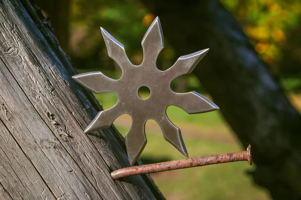 Shuriken (throwing star), traditional japanese ninja cold weapon stuck in wooden background