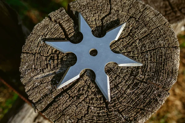 Shuriken (throwing star), traditional japanese ninja cold weapon stuck in wooden background