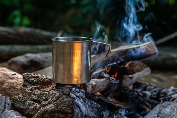 steel cup on an open fire in nature. Cooking on fire. Camping in