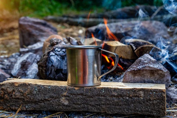 steel cup on an open fire in nature. Cooking on fire. Camping in