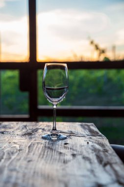 Gün batımında üzüm bağlarının üzerinde bir kadeh şarap..