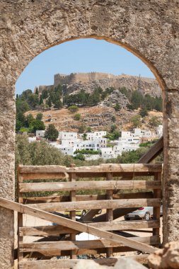 Güneşli bir günde, Akropolis 'in antik kalıntılarıyla Lindos Town ve Castle' daki taş kemer açıklığından uzak bir manzara. Yunanistan 'ın Rodos adası. Avrupa.