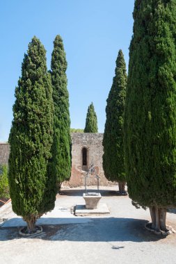 Filerimos Manastırı. Bahçedeki eski kuyu selvi ağaçlarıyla çevrili. Rodos Adası, Yunanistan. Avrupa.