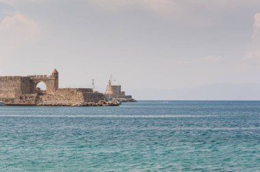 View at old fortification in old port from Akti Sachtouri sea promenade with Delphinia, sculpture of Dolphins. Rhodes, Old Town, Island of Rhodes, Greece, Europe.