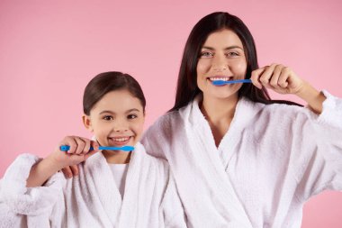 Anne ve kızı önlük içinde diş fırçaları.