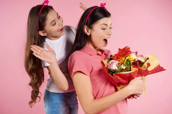 Nice little daughter gives flowers to beautiful