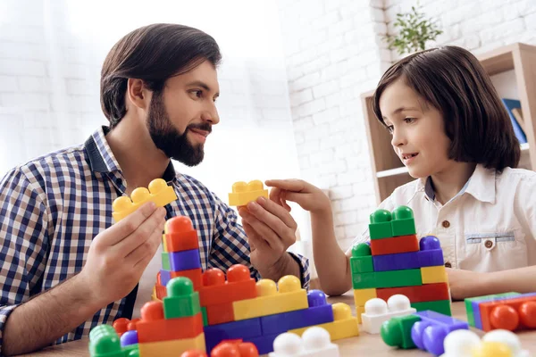 Père heureux et fils jouent avec des blocs en plastique colorés . — Photo