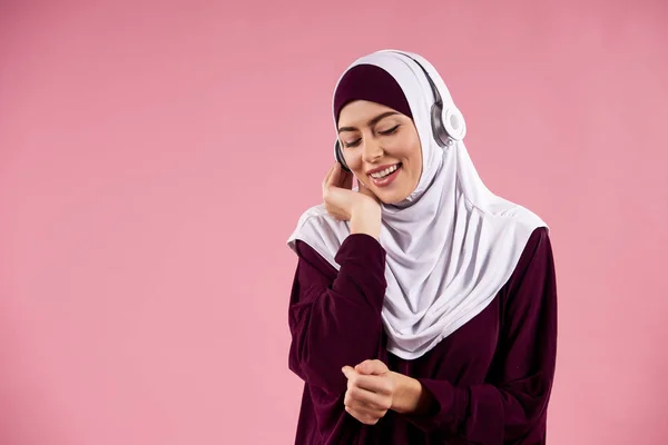 Arab woman in hijab listens to music on headphones